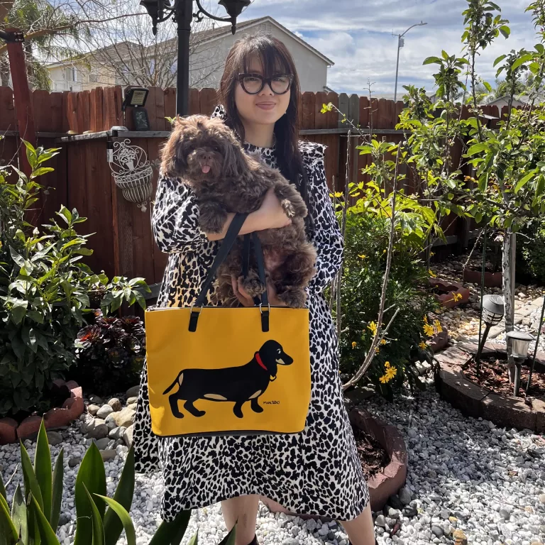 Woman in cow print dress holding dog and yellow purse