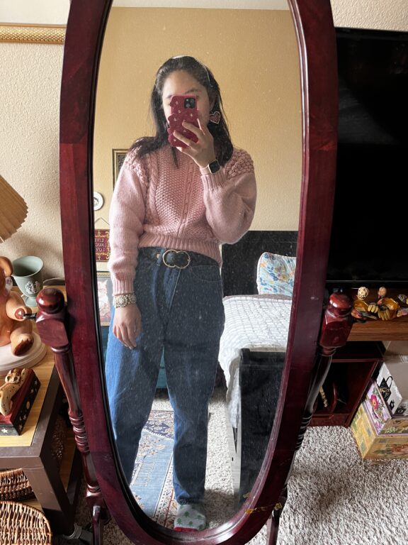 Woman in pink wool sweater and belted blue jeans